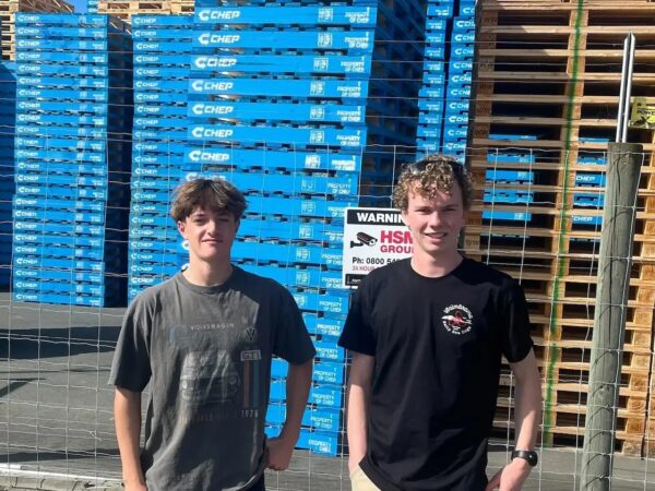 Students standing in front of a stack of pallets